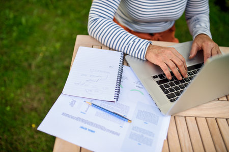 Top view of active senior woman working outdoors in garden, home office concept.