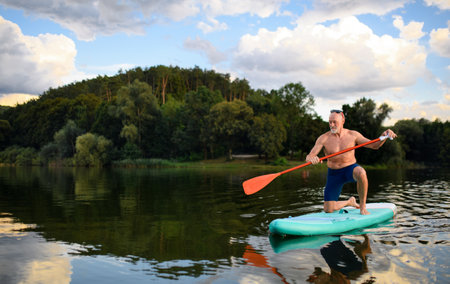 Senior man paddleboarding on lake in summer. Copy space.の写真素材