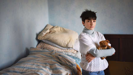 Poor sad small girl standing and looking at camera indoors at home, poverty concept.の写真素材