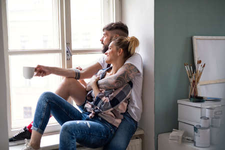 Mid adults couple sitting indoors at home, relocation and diy concept.の写真素材