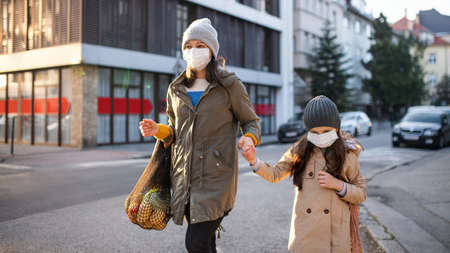Mother with small daughter with shopping bags outdoors on street, concept.の写真素材