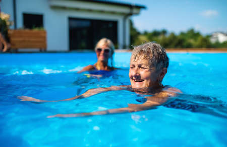 Portrait of senior woman in swimming pool outdoors in backyard.の写真素材