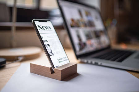 Smartphone in wooden stand holder on table indoors at home or on office.の写真素材