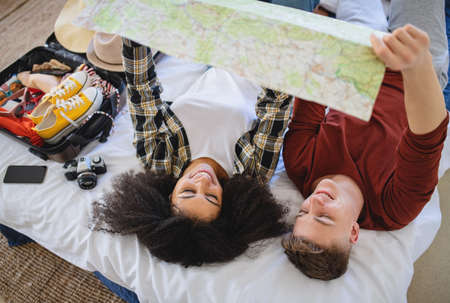 Young couple with map packing for holiday at home.の写真素材