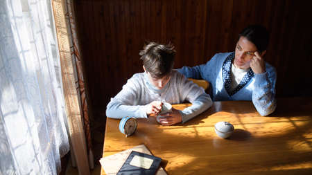 Portrait of sad poor mature mother with small daughter indoors at home, poverty concept.の写真素材