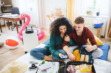 Young couple with laptop packing for summer holidayの写真素材