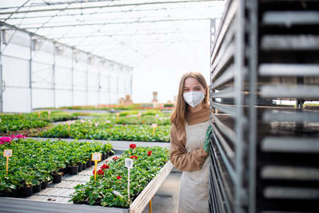 Young woman working in greenhouse in garden centerの写真素材