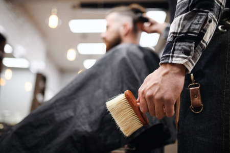 Man client in barber shop, unrecognizable barber holding brush.の写真素材