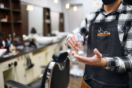 Unrecognizable man haidresser disinfecting hands in barber shop, coronavirus and new normal concept.の写真素材