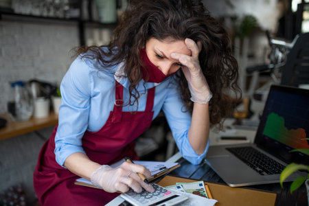 Frustrated coffee shop manager calculating figures in cafe, small business and new normal concept.の写真素材