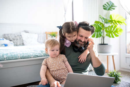 Father working with small daughters in bedroom, home office concept.の写真素材