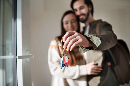Young couple with keys moving in new flat, new home and relocation concept.の写真素材