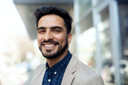 Portrait of young businessman commuter outdoors in city, looking at camera.