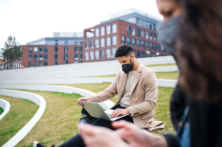 Man with laptop working outdoors in park in cityの写真素材