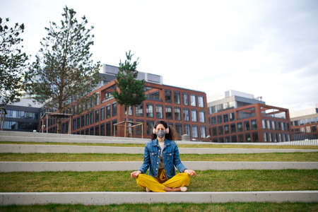 Woman with headphones doing yoga outdoors in park in city