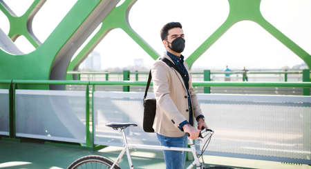 Young business man commuter with bicycle going to work outdoors on bridge in cityの写真素材