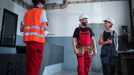 Group of workers with helmet indoors in factory, discussing issues.の写真素材