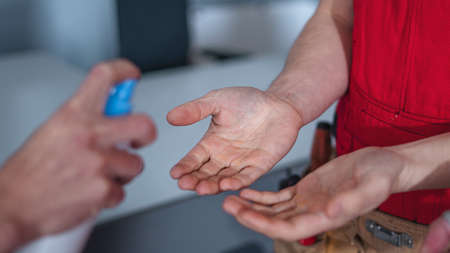 Midsection of workers indoors in factory, disinfecting handsの写真素材