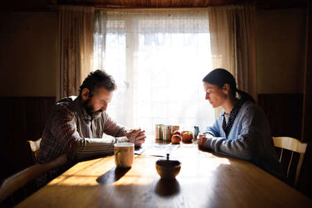 Portrait of sad poor mature couple praying at the table indoors at home, poverty concept.の写真素材