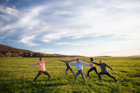 Group of seniors with sport instructor doing exercise outdoors in nature, active lifestyle.の写真素材