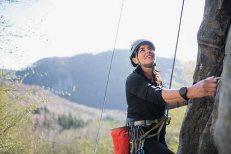 Senior woman climbing rocks outdoors in nature, active lifestyle.の写真素材
