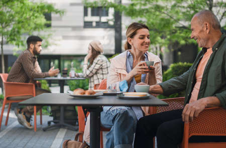 Woman with senior father in cafe outdoors in city, life after covid-19 vaccination and back to...