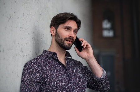 Portrait of young businessman standing indoors, using smarpthone.