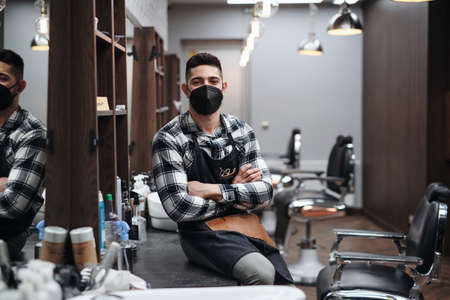 Young man haidresser disinfecting surfaces in barber shop, new normal concept.の写真素材