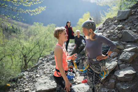 Senior woman with instructor climbing rocks outdoors in nature, active lifestyle.