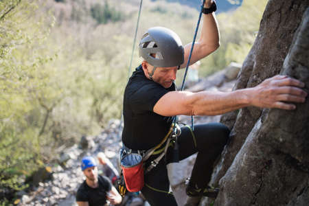 Senior man with instructor climbing rocks outdoors in nature, active lifestyle.の写真素材