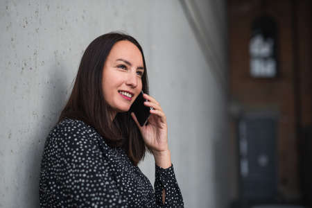 Portrait of mid adult businesswoman standing indoors in office, using smartphone.の写真素材