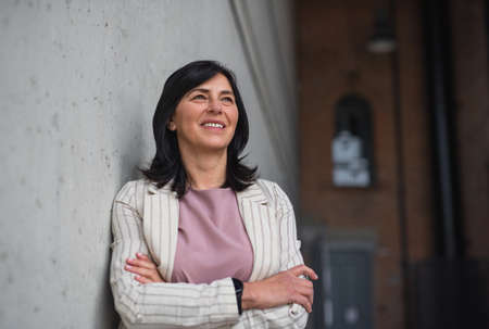 Portrait of senior businesswoman standing indoors in office.
