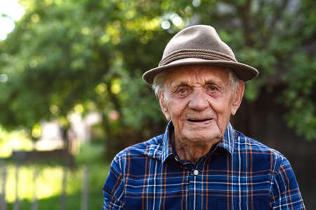 Portrait of elderly man standing outdoors in garden, looking at camera.の写真素材