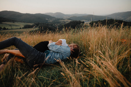 Young couple on a walk in nature in countryside, lying in grass having fun.の写真素材