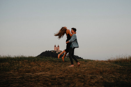 Young couple on a walk in nature at dusk in countryside, having fun hugging.の写真素材