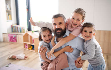 Father with three daughters indoors at home, looking at camera.の写真素材