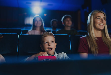 Mother with happy small children in the cinema, watching film.の写真素材