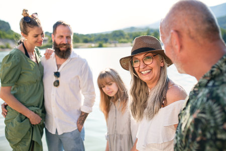 Happy multigeneration family on summer holiday, walking by lake.