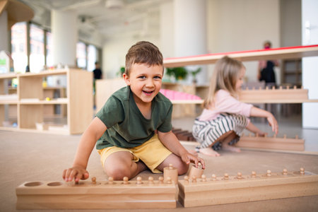 Group of small nursery school children playing indoors in classroom, montessori learning.の写真素材
