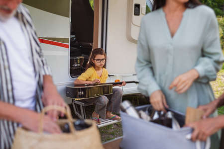 Multi-generation family unpacking by car, caravan holiday trip.の写真素材