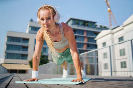 Mid adult woman doing push-ups outdoors in city, exercise and healthy lifestyle concept.