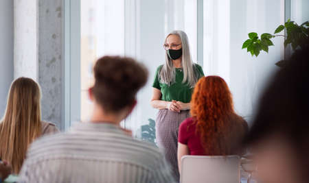Rear view of university students with teacher studying indoors, coronavirus and back to normal...