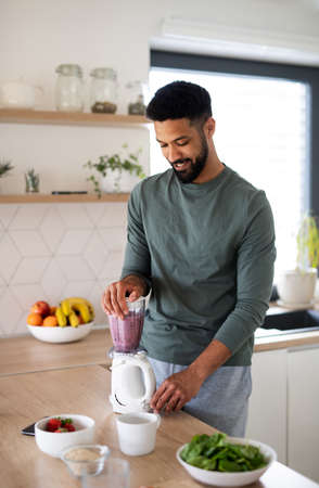 Young man preparing healthy breakfast indoors at home, making milk shake.の写真素材