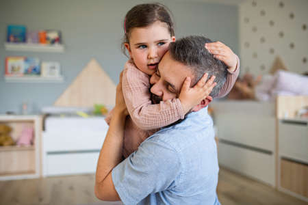 Happy father with daughter indoors at home, hugging.の写真素材