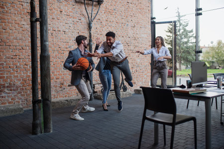 Group of cheerful young businesspeople playing basketball in office, taking a break concept.の写真素材