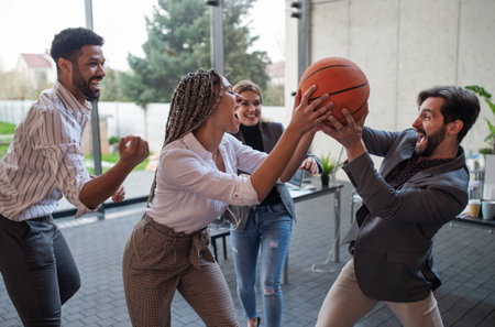 Group of cheerful young businesspeople playing basketball in office, taking a break concept.の写真素材