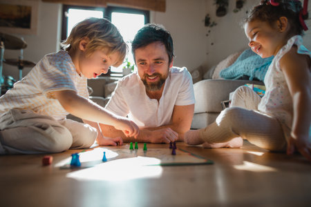 Mature father with two small children resting indoors at home, playing board games.の写真素材