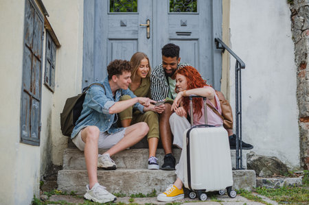 Group of young people outdoors on trip in town, using online map on smartphone.