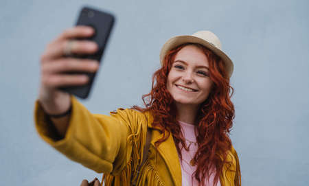 Young woman tourist outdoors against white background on trip in town, taking selfie.