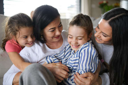 Happy small girls with mother and grandmother indoors at home, hugging.の写真素材